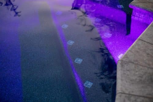 close up on swimming pool stairs lit with purple lights - built by Orange County custom pool builder