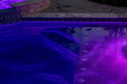 water in residential pool at night lit by purple lights in Orange County pool