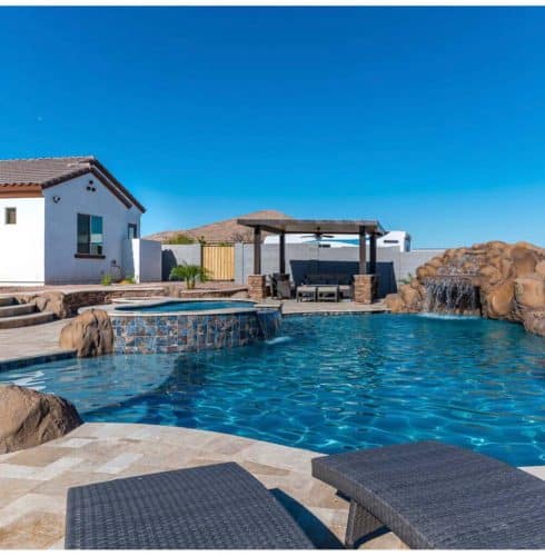 SoCal luxury pool with natural waterfall rock features, spa, and poolside lounge