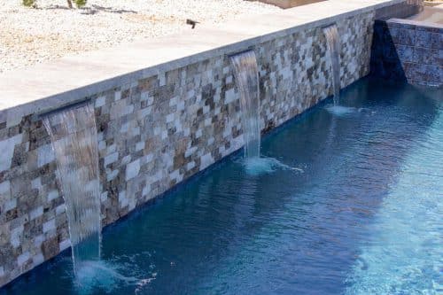 Temecula backyard pool design with waterfall features and tan surfacing