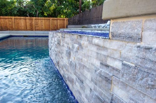custom backyard pool design with built-in spa and blue tiles