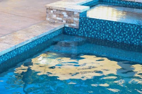 backyard pool with blue tiles and tan rock
