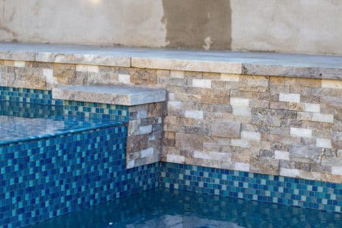 custom backyard pool construction with blue tiles and tan rock Chino Hills