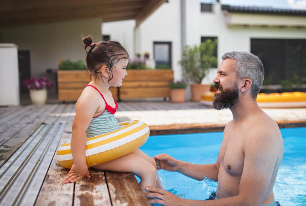 father and daughter in inground pool