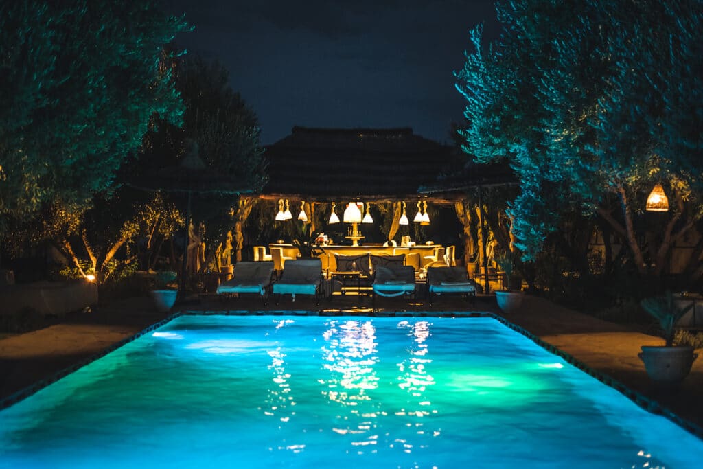 swimming pool at night with pool lights lighting inside and around the pool