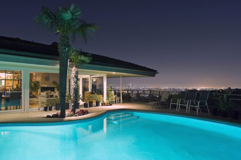 backyard with hillside pool lit up at night