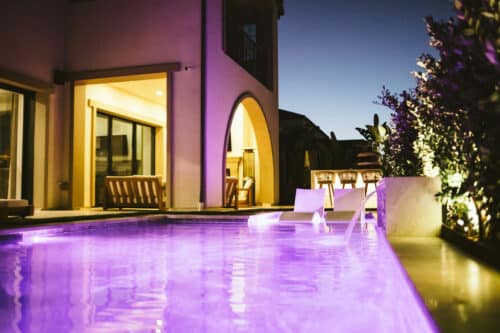 Pool with purple lights and lit room behind