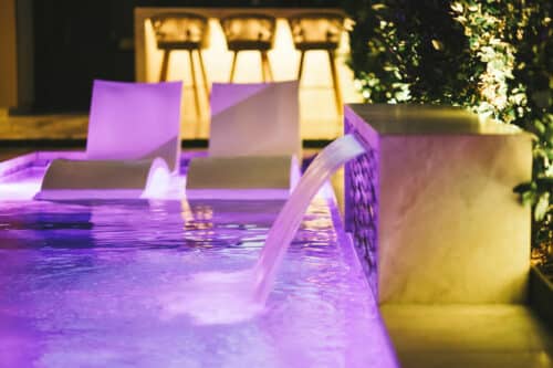 Purple lit pool with waterfall fountain
