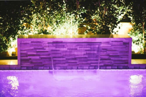 Purple lit pool with water fall fountain