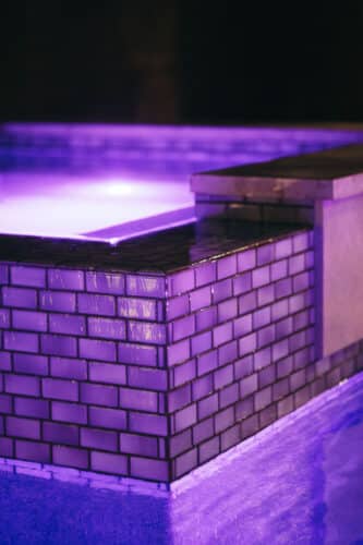 Purple lit pool with waterfall over side
