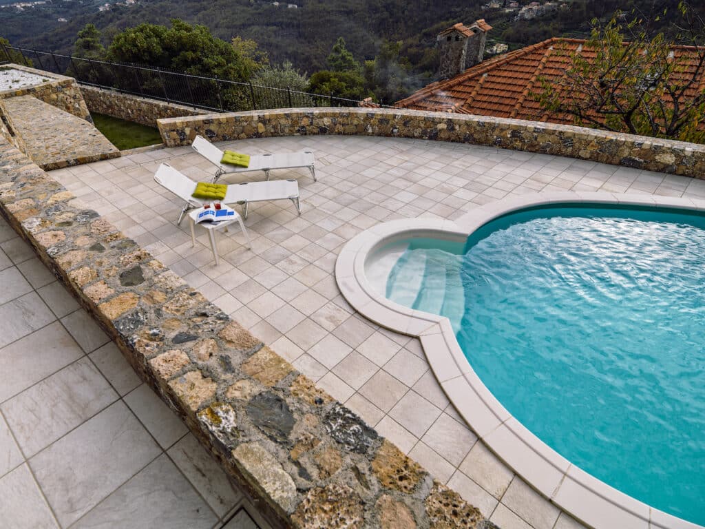 overhead view of a modern pool in a backyard with tile and lounge chairs
