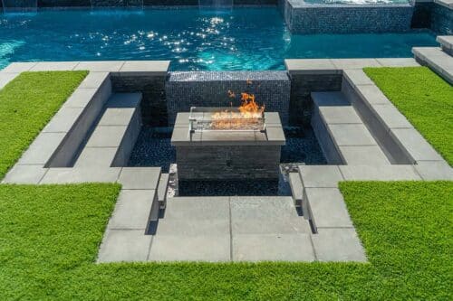 custom backyard pool with a fire pit