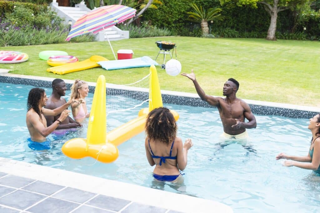 group of friends playing swimming pool games at backyard pool party